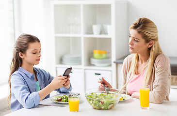 Image showing sad woman looking at her daughter with smartphone