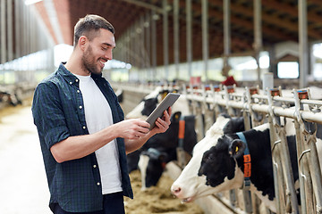 Image showing young man with tablet pc and cows on dairy farm