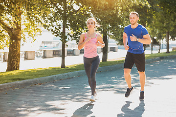 Image showing The sporty woman and man jogging at park in sunrise light