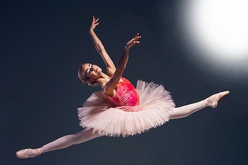 Image showing Beautiful female ballet dancer on a dark background. Ballerina is wearing pink tutu and pointe shoes.