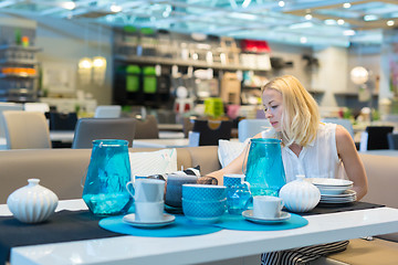 Image showing Woman choosing the right decor for her apartment in a modern home furnishings store.