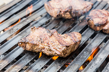 Image showing Beef steaks on grill with flames.