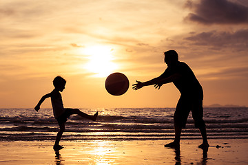 Image showing Father and son playing on the beach at the sunset time.