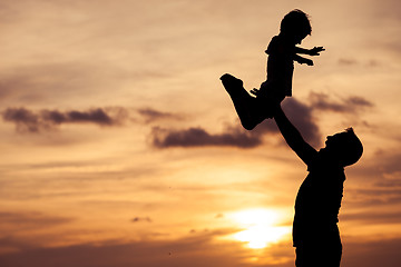 Image showing Father and son playing on the beach at the sunset time.