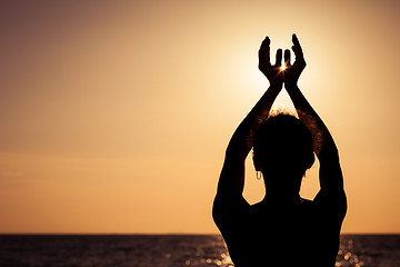 Image showing woman open arms under the sunset at sea.