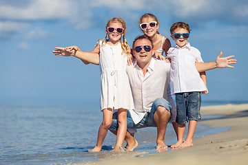 Image showing Father and children playing on the beach at the day time.