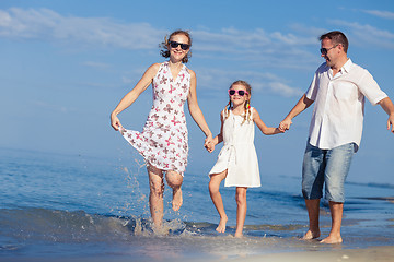 Image showing Happy family walking on the beach at the day time.