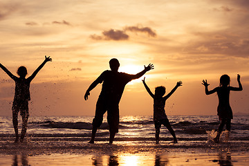 Image showing Father and children playing on the beach at the sunset time.