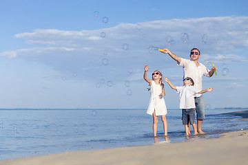 Image showing Father and children playing on the beach at the day time.