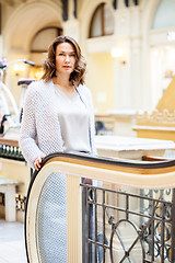 Image showing woman in a light knitted coat near an escalator