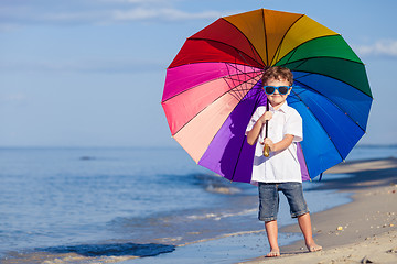 Image showing Little boy with umbrella standing on the beach