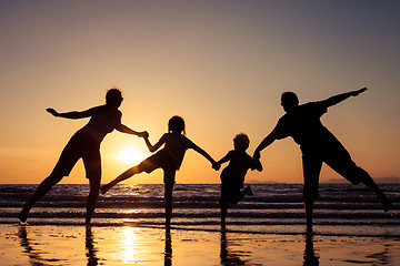 Image showing Silhouette of happy family who playing on the beach at the sunse