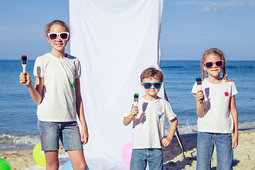 Image showing Two sisters and brother playing on the beach at the day time.