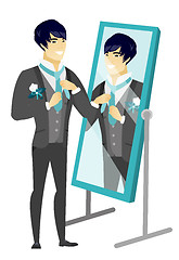 Image showing Groom looking in the mirror and adjusting tie.