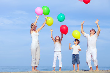 Image showing Happy family jumping on the beach at the sunset time.