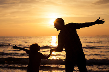 Image showing Father and son playing on the beach at the sunset time.