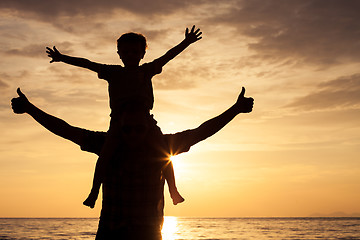 Image showing Father and son playing on the beach at the sunset time.