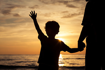 Image showing Father and son playing on the beach at the sunset time.