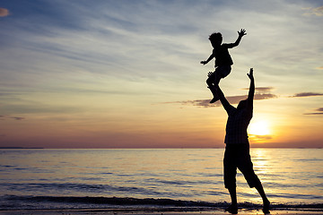 Image showing Father and son playing on the beach at the sunset time.