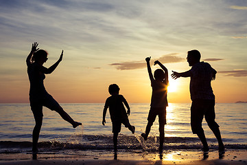 Image showing Silhouette of happy family who playing on the beach at the sunse