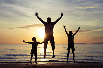 Image showing Father and children playing on the beach at the sunset time.