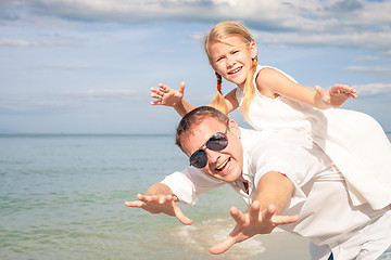 Image showing Father and daughter playing on the beach at the day time.