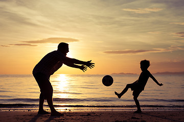 Image showing Father and son playing on the beach at the sunset time.