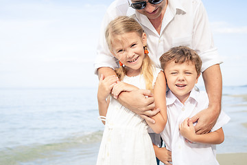 Image showing Father and children playing on the beach at the day time.