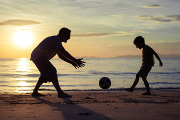 Image showing Father and son playing on the beach at the sunset time.