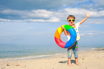 Image showing Little boy with rubber ring standing on the beach