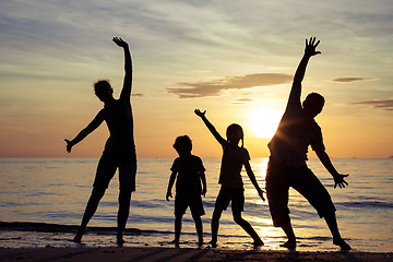 Image showing Silhouette of happy family who playing on the beach at the sunse