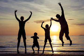 Image showing Silhouette of happy family who playing on the beach at the sunse