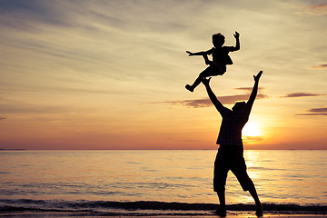 Image showing Father and son playing on the beach at the sunset time.