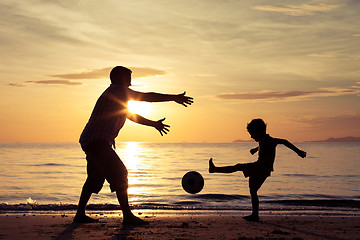 Image showing Father and son playing on the beach at the sunset time.