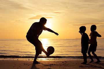 Image showing Father and children playing on the beach at the sunset time.