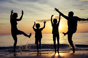 Image showing Silhouette of happy family who playing on the beach at the sunse