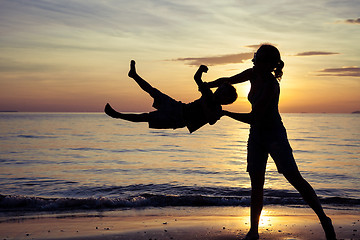 Image showing Mother and son playing on the beach at the sunset time.