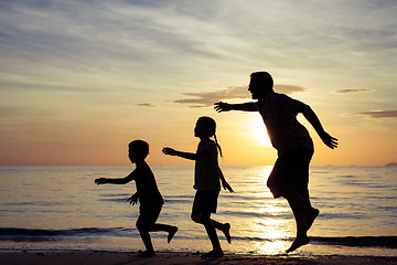 Image showing Father and children playing on the beach at the sunset time.