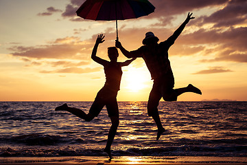 Image showing Happy family jumping on the beach at the sunset time.