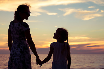 Image showing Mother and daughter playing on the beach at the sunset time.