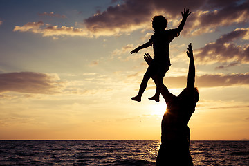 Image showing Father and son playing on the beach at the sunset time.