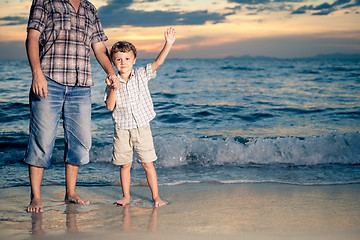 Image showing Father and son playing on the beach at the sunset time.