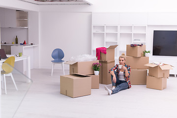 Image showing woman with many cardboard boxes sitting on floor