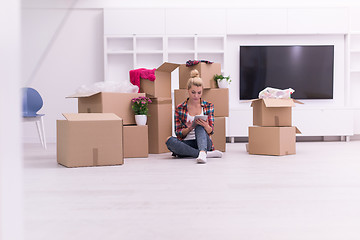 Image showing woman with many cardboard boxes sitting on floor