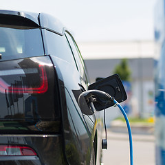 Image showing Power supply plugged into an electric car being charged.