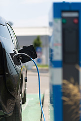 Image showing Power supply plugged into an electric car being charged.