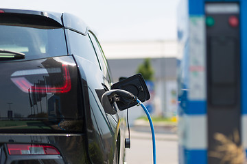 Image showing Power supply plugged into an electric car being charged.