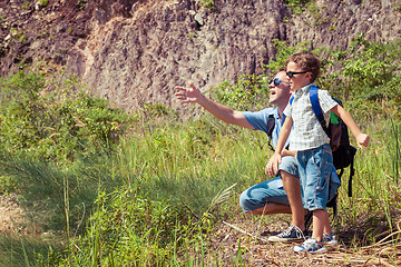 Image showing Father and son siting near the pond at the day time.