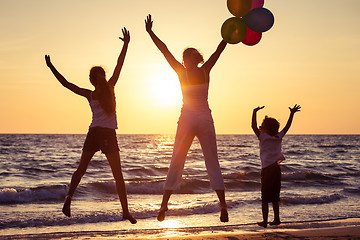 Image showing Mother and children playing on the beach at the sunset time.