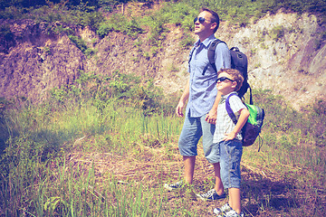 Image showing Father and son standing near the pond at the day time. 